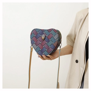 Détail du sac à main en forme de cœur avec texture tissée colorée et boucle aigle