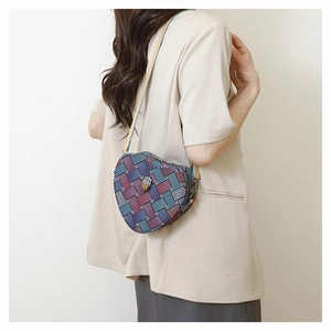 Détail du sac bandoulière tissé en forme de cœur avec motif écossais et boucle métal