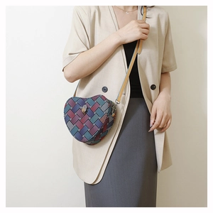 Vue détaillée du sac bandoulière en forme de cœur avec texture en tweed et logo aigle