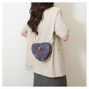 Modèle portant un sac bandoulière en forme de cœur avec motif tissé et tête d'aigle
