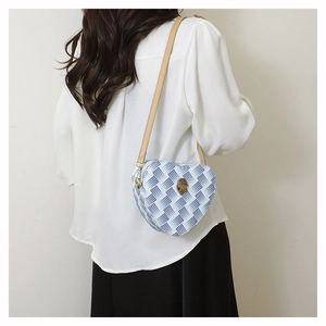 Détail d'un sac bandoulière en forme de cœur avec motif serpent et logo tête d'aigle
