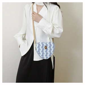 Détail du sac bandoulière cœur avec motif vagues bleues et fermoir tête d'aigle doré