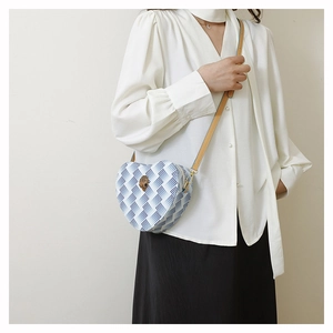 Détail du sac à bandoulière en forme de cœur avec motif losanges et emblème d'aigle