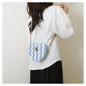 Détail du sac bleu en forme de cœur avec texture serpent et ornement d'aigle en métal