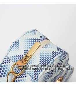 Détail de la fermeture éclair dorée sur sac blanc avec motif à pois bleus