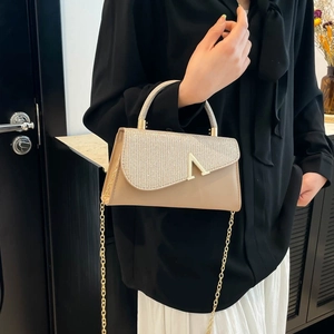Elegant champagne glitter crossbody bag with gold V hardware and chain strap