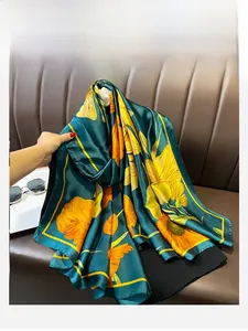 Detail of oversized dark green silk scarf with large yellow floral patterns and rolled edges