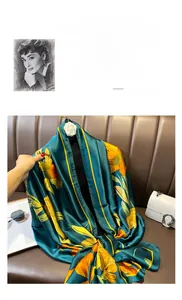 Detail of silk scarf with yellow sunflowers on dark green fabric draped over leather