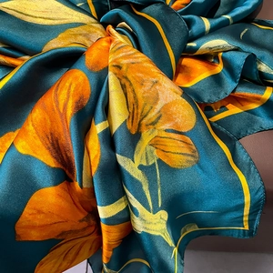 Detail of silk scarf showing glossy satin texture and vibrant orange floral patterns