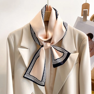 Eleganter champagner-rosa Seidenschal mit Kettendesign am Revers eines Blazers gebunden