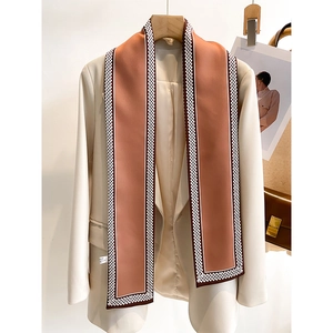Eleganter orange-brauner langer Seidenschal mit geometrischem Rand auf hellem Blazer