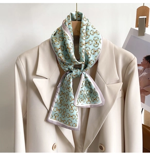 Détail d'un foulard en soie avec motif mors doré sur un tissu vert menthe