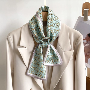Foulard étroit en soie à motif mors de cheval noué sur un revers de blazer