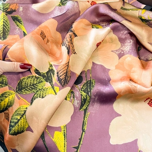 Close-up of silky purple square scarf showing pink floral prints and soft fabric folds