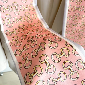 Détail macro du foulard étroit en soie rose avec motif mors et bords en satin doux