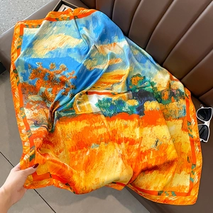 Close-up of a silk scarf with landscape oil painting prints on a leather sofa