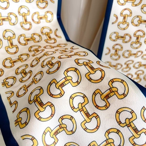 Détail d'un foulard en soie avec imprimé mors, bordures bleu marine et satiné