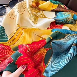 Detail of silk-like scarf featuring vibrant red and yellow ginkgo leaf prints