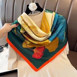 Detail of silk scarf with ginkgo leaf pattern and vibrant contrast orange edges