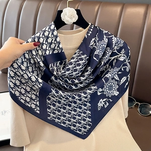 Close-up of luxury dark blue silk scarf with vintage floral patterns and logo print