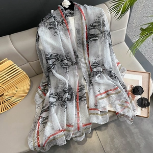 Long chiffon scarf with snakeskin and chain print draped on a modern sofa for vacation