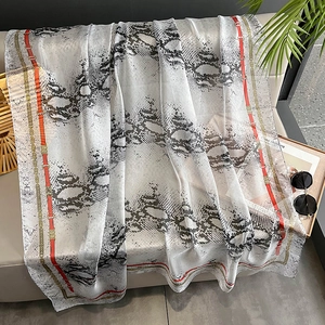 Long snake print beach shawl with gold chain and red belt border on an elegant sofa