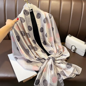 Elegante sciarpa in seta con stampa camelia grigio champagne drappeggiata su manichino