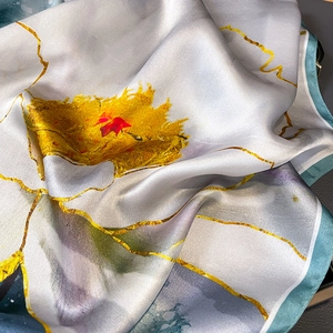 Élégant foulard en soie à motif floral jaune et bordure verte sur surface texturée