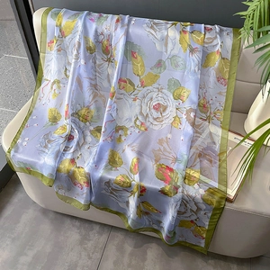Écharpe en soie violet clair avec motifs de roses roses sur un canapé en cuir beige