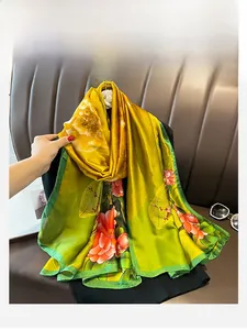 Detail of vibrant yellow and green silk scarf with bold red floral pattern on sofa