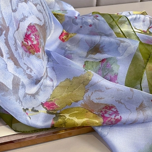 Vue macro d'un foulard en soie bleu clair avec imprimé fleuri et texture satinée