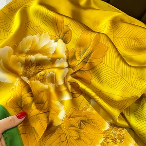 Detailed view of yellow floral silk scarf with large peony print and green border
