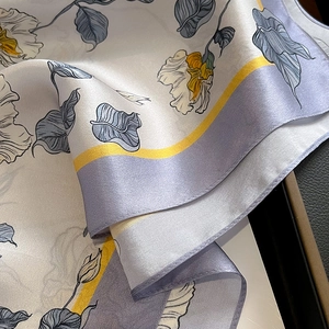 Carré de soie élégant à motif floral avec bordure lilas sur un coffret de luxe