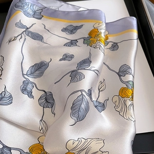 Détail d'un foulard en soie avec imprimé rose jaune et texture satinée sur coffret