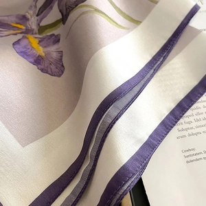 Detail of silk scarf featuring purple iris patterns and premium stitched hem edges