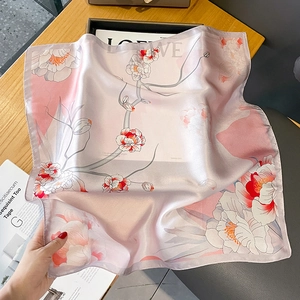 Carré en soie rose avec imprimé floral et bords roulés à la main sur table en bois