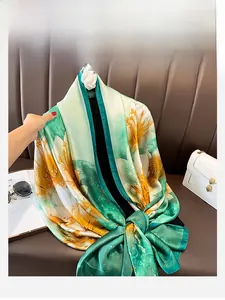 Detailed close-up of emerald and yellow silk scarf with lily print on luxury leather sofa
