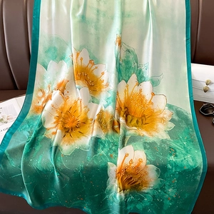 Elegant lotus silk scarf with floral print and green gradient on leather sofa