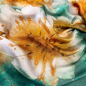 Detail of silk satin scarf showing emerald green fabric and vibrant lily floral prints