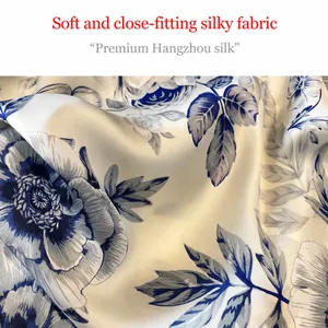 Detail eines seidigen Strandtuchs mit elegantem Blumenmuster auf champagnerfarbenem Satin