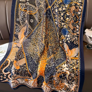 Artistic printed silk scarf with floral and bird motifs on a luxury leather sofa