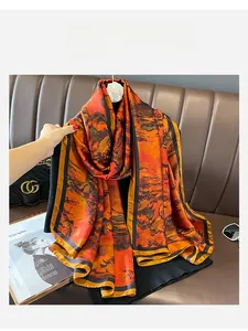 Detailed view of silk scarf with orange landscape print on a luxury leather background