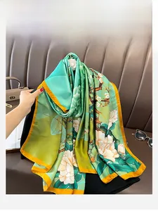 Detail of elegant floral silk scarf with vibrant green base and orange rolled edges