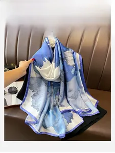 Dettaglio di una sciarpa di seta blu e bianca con grandi motivi floreali e bordi eleganti