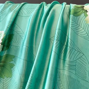 Mint green silk scarf with lotus prints, showing luxurious texture and draped fabric