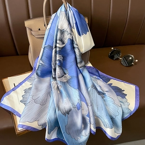 Elegante sciarpa in seta con stampa floreale blu drappeggiata su una borsa chic