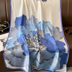 Elegante sciarpa in finta seta con fiori blu e crema su un divano di pelle