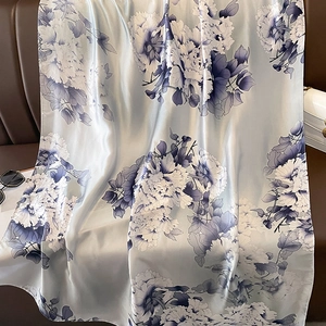 Elegant blue peony print satin scarf shawl draped on a brown leather sofa for sun protection