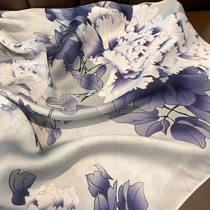 Elegant silk scarf with blue peony print and smooth texture shown in detailed folds