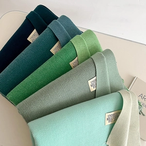 Detail of multi-tone green scarves showing twill knit texture and woven label decor